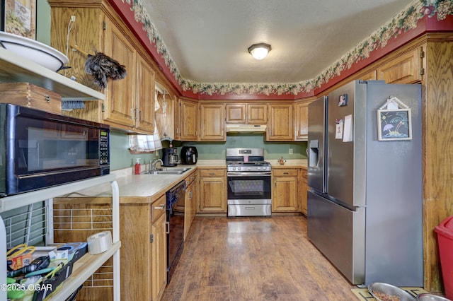 610 N Madison St, Webb City, MO 64870 - kitchen featuring black appliances, under cabinet range hood, light countertops, dark wood-style flooring, and brown cabinetry