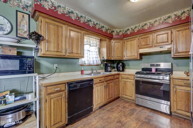 610 N Madison St, Webb City, MO 64870 - kitchen featuring black appliances, under cabinet range hood, a sink, light countertops, and dark wood-type flooring