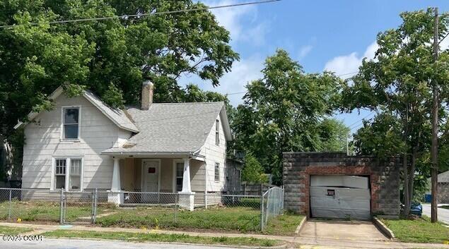 911 W 2nd St, Joplin, MO 64801 - view of front facade with a fenced front yard, a chimney, concrete driveway, a gate, and an outdoor structure