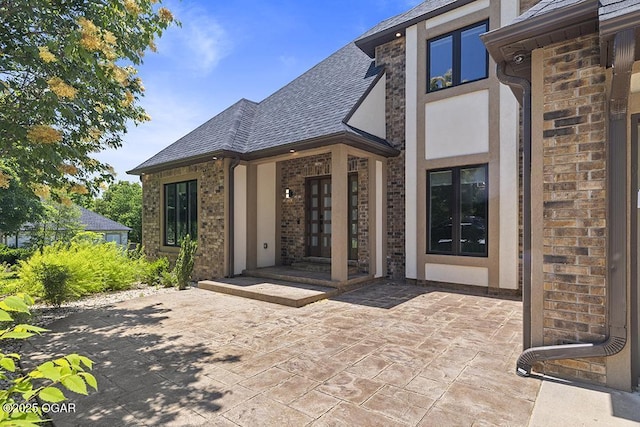 3802 Fawn Trl, Joplin, MO 64804 - property entrance with french doors, a patio area, roof with shingles, stucco siding, and brick siding