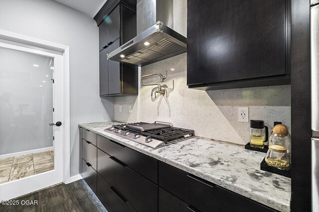 3802 Fawn Trl, Joplin, MO 64804 - kitchen with wall chimney range hood, dark cabinetry, stainless steel gas cooktop, tasteful backsplash, and baseboards