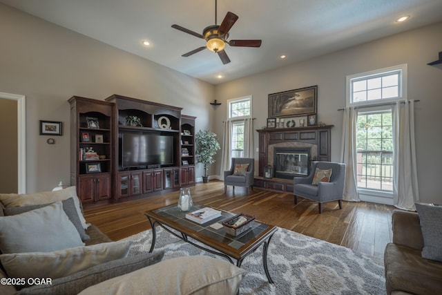 20951 Jasmine Ln, Webb City, MO 64870 - living room with wood finished floors, ceiling fan, a glass covered fireplace, a high ceiling, and recessed lighting