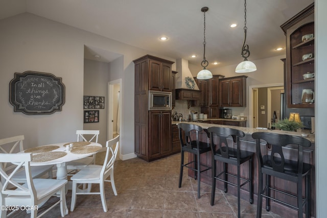 20951 Jasmine Ln, Webb City, MO 64870 - kitchen with stainless steel microwave, dark brown cabinetry, a peninsula, recessed lighting, and a breakfast bar area