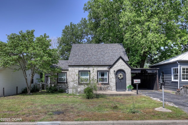 514 S Brownell Ave, Joplin, MO 64801 - tudor house with stone siding, a carport, roof with shingles, a front lawn, and driveway