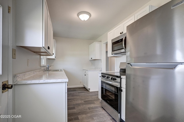3124 Missouri Ave, Joplin, MO 64804 - kitchen with stainless steel appliances, a sink, dark wood-type flooring, light countertops, and white cabinetry