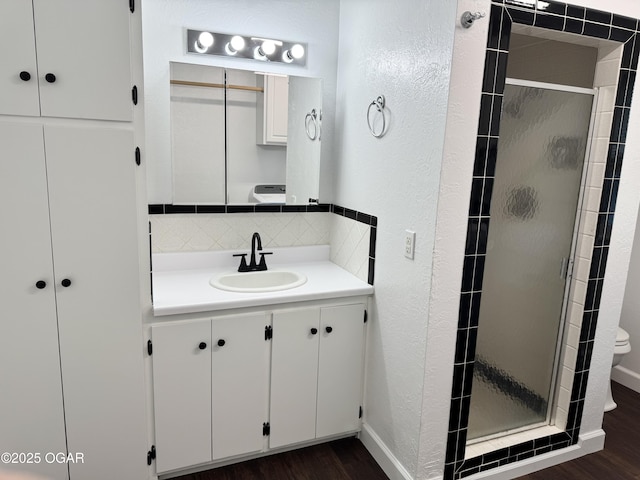 2119 S Main St, Carthage, MO 64836 - bathroom featuring wood finished floors, a shower stall, vanity, backsplash, and a textured wall