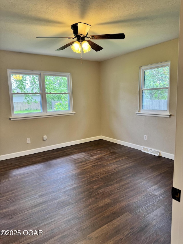 2119 S Main St, Carthage, MO 64836 - unfurnished room featuring healthy amount of natural light, dark wood-style floors, ceiling fan, baseboards, and a textured ceiling
