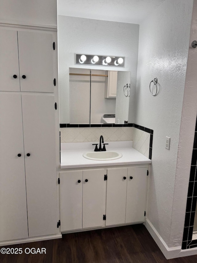 2119 S Main St, Carthage, MO 64836 - bathroom featuring a textured wall, vanity, backsplash, wood finished floors, and baseboards