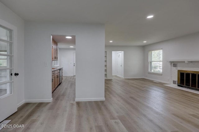 328 E 33rd St, Joplin, MO 64804 - unfurnished living room featuring light wood-style floors, built in shelves, baseboards, a fireplace, and recessed lighting