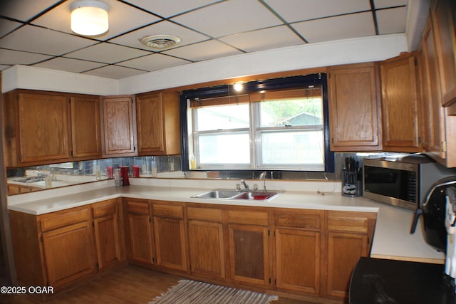 423 Mower St, Duenweg, MO 64841 - kitchen featuring stainless steel microwave, a sink, brown cabinets, light countertops, and light wood-style floors