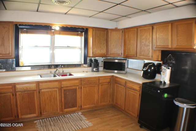 423 Mower St, Duenweg, MO 64841 - kitchen with stainless steel microwave, a sink, light countertops, brown cabinetry, and light wood finished floors