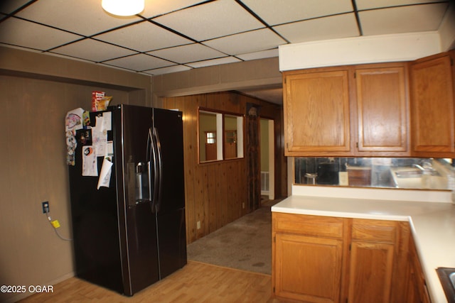 423 Mower St, Duenweg, MO 64841 - kitchen with black fridge with ice dispenser, light countertops, light wood finished floors, brown cabinets, and wooden walls