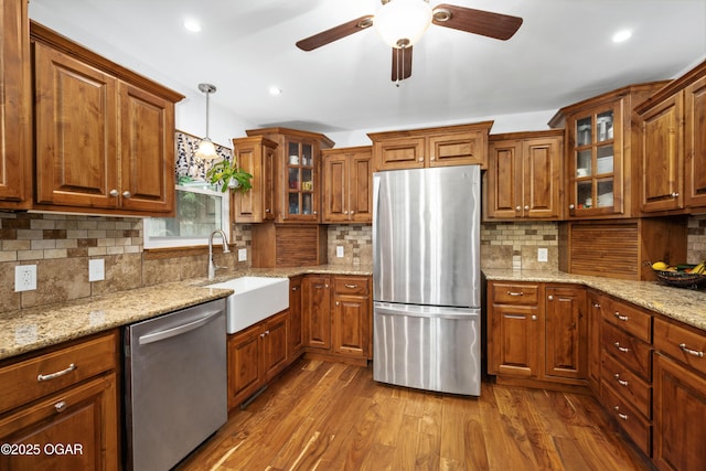 3431 Hawthorn Dr, Joplin, MO 64804 - kitchen featuring stainless steel appliances, a sink, brown cabinetry, tasteful backsplash, and a ceiling fan