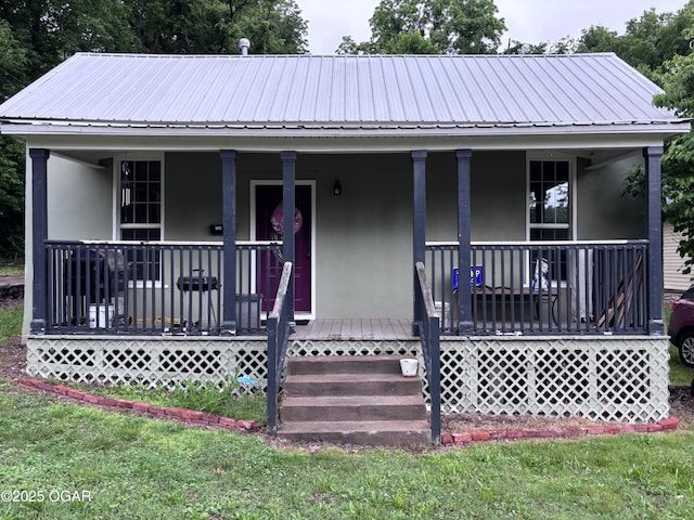 324 W Hill St, Neosho, MO 64850 - view of front of house with stucco siding, a porch, and metal roof