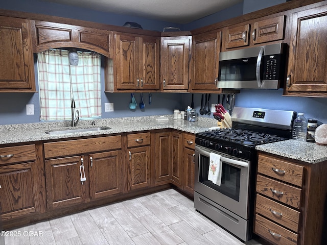 324 W Hill St, Neosho, MO 64850 - kitchen with stainless steel appliances, a sink, light stone counters, and light wood-style flooring