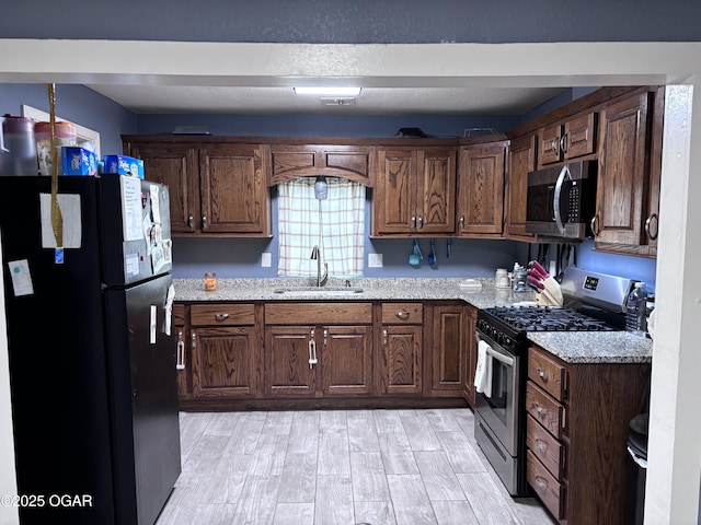 324 W Hill St, Neosho, MO 64850 - kitchen featuring appliances with stainless steel finishes, a sink, light wood-type flooring, and light stone counters