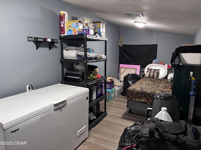 324 W Hill St, Neosho, MO 64850 - bedroom with refrigerator, light wood-type flooring, and a textured ceiling