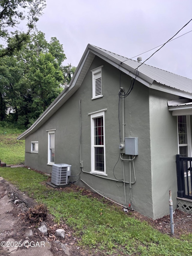 324 W Hill St, Neosho, MO 64850 - view of side of home featuring stucco siding, central AC unit, and metal roof