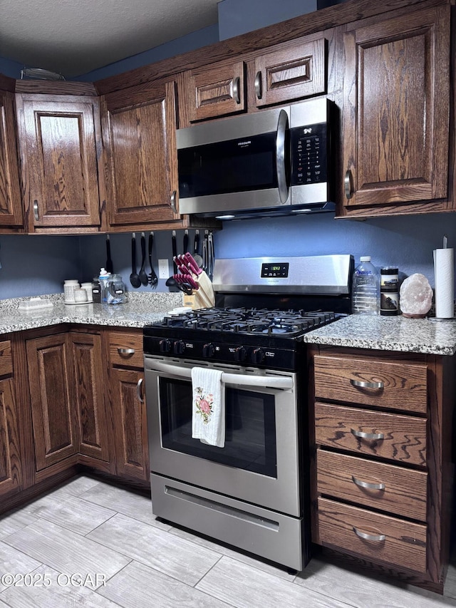 324 W Hill St, Neosho, MO 64850 - kitchen featuring appliances with stainless steel finishes, light stone counters, and dark brown cabinetry