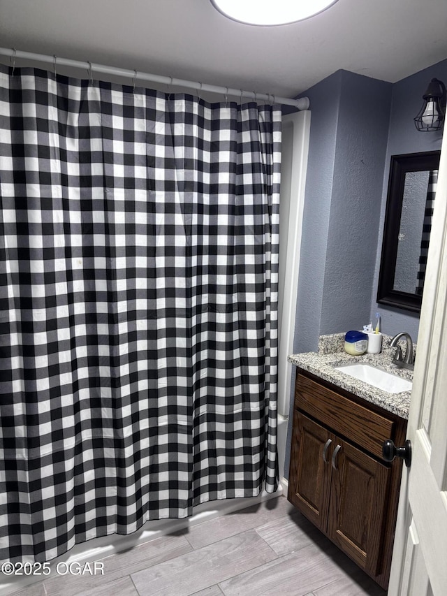324 W Hill St, Neosho, MO 64850 - full bath featuring vanity, a textured wall, wood finished floors, and a shower with shower curtain