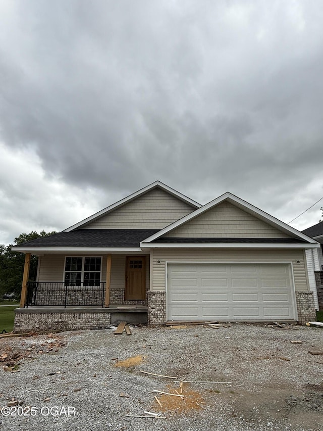 2006 E Quincy St, Joplin, MO 64801 - view of front facade with covered porch, an attached garage, gravel driveway, and brick siding
