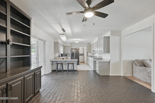 2722 Wisconsin Ave, Joplin, MO 64804 - kitchen featuring stainless steel appliances, open floor plan, brick floors, a ceiling fan, and baseboards