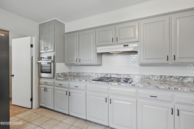 2722 Wisconsin Ave, Joplin, MO 64804 - kitchen with oven, black electric stovetop, under cabinet range hood, backsplash, and light stone countertops