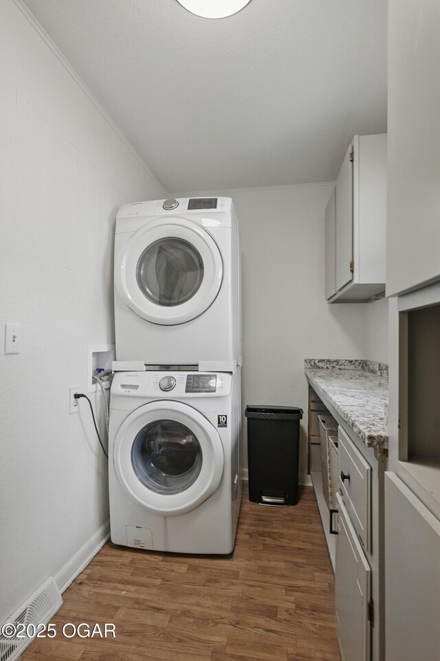 2722 Wisconsin Ave, Joplin, MO 64804 - washroom featuring stacked washer / dryer, cabinet space, wood finished floors, and baseboards