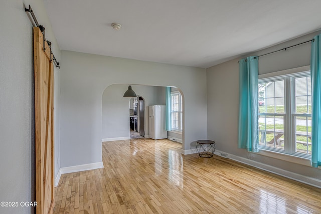 2502 S Tyler Ave, Joplin, MO 64804 - spare room featuring arched walkways, light wood-style flooring, a barn door, and a smoke detector