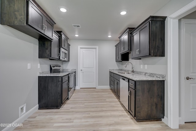 kitchen with stainless steel appliances, light stone counters, light wood finished floors, recessed lighting, and dark brown cabinetry