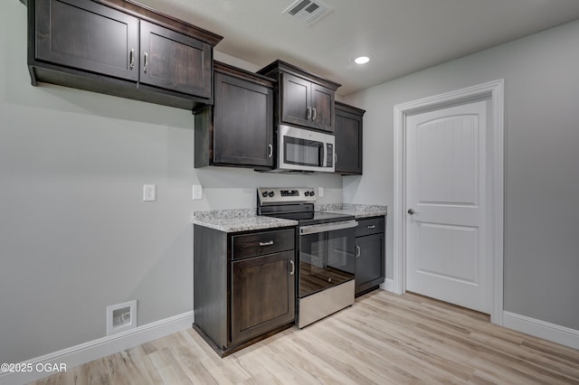 kitchen featuring appliances with stainless steel finishes, light wood finished floors, dark brown cabinets, light stone counters, and recessed lighting