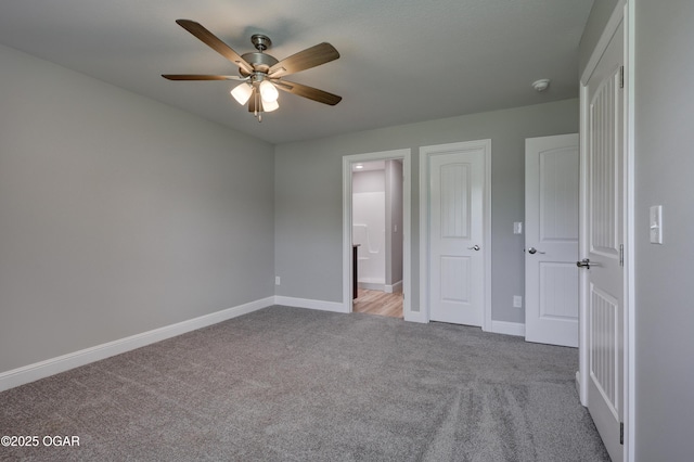 unfurnished bedroom with carpet flooring, ensuite bathroom, and a ceiling fan