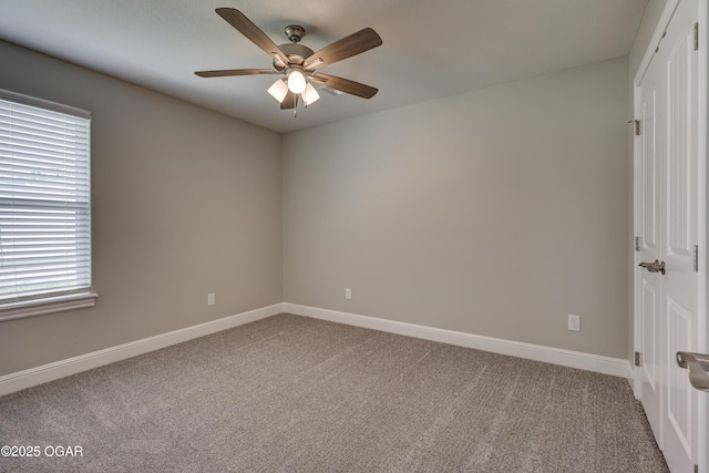 carpeted empty room featuring ceiling fan and baseboards
