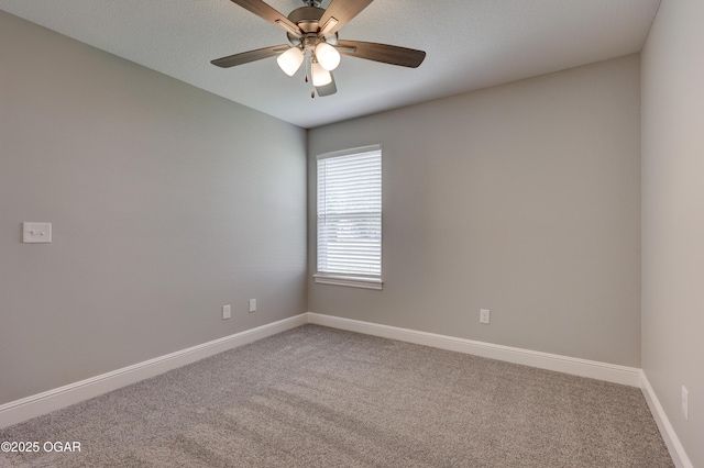 carpeted spare room with a ceiling fan and baseboards