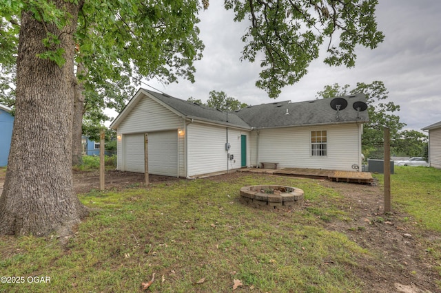 2413 Rolla St, Joplin, MO 64801 - rear view of property with an outdoor fire pit, a garage, a yard, a wooden deck, and cooling unit
