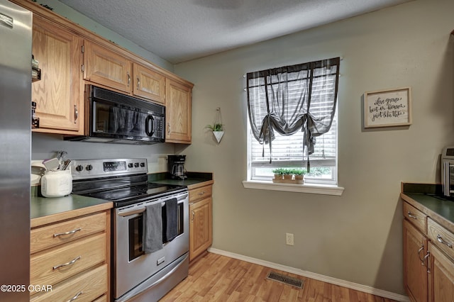 2413 Rolla St, Joplin, MO 64801 - kitchen with stainless steel appliances, light wood-style floors, dark countertops, baseboards, and a textured ceiling