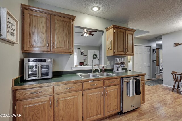 2413 Rolla St, Joplin, MO 64801 - kitchen with dishwasher, a sink, light wood-type flooring, dark countertops, and a textured ceiling