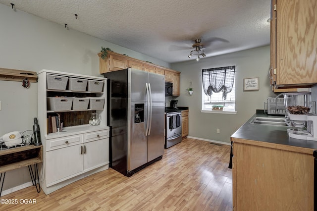 2413 Rolla St, Joplin, MO 64801 - kitchen featuring stainless steel appliances, light wood finished floors, a textured ceiling, baseboards, and a sink