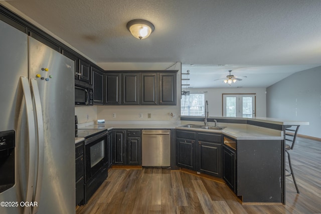 522 E Yale St, Liberal, MO 64762 - kitchen featuring black appliances, a peninsula, a sink, dark wood-type flooring, and a textured ceiling