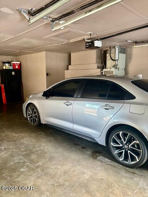 1300 S Baker Blvd, Carthage, MO 64836 - garage featuring a garage door opener and freestanding refrigerator