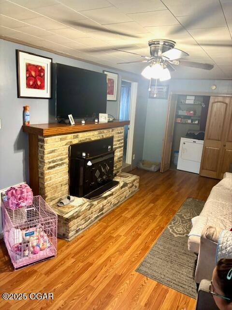 1300 S Baker Blvd, Carthage, MO 64836 - living area featuring washer / clothes dryer, ceiling fan, a fireplace with raised hearth, and wood finished floors