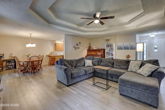 1241 Douglas Ct, Carthage, MO 64836 - living area with a raised ceiling, a textured ceiling, a chandelier, a ceiling fan, and light wood-type flooring
