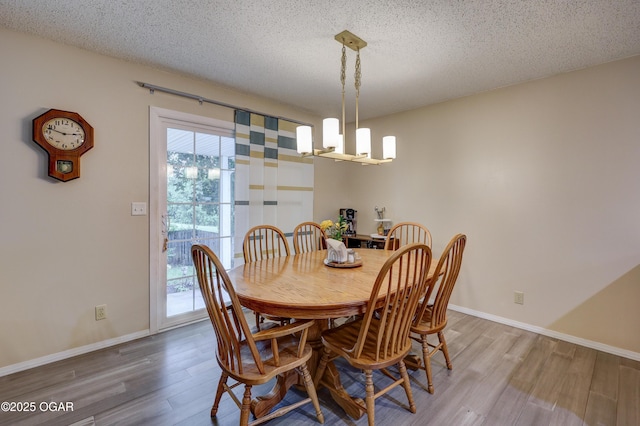 1241 Douglas Ct, Carthage, MO 64836 - dining space featuring a chandelier, wood finished floors, a textured ceiling, and baseboards