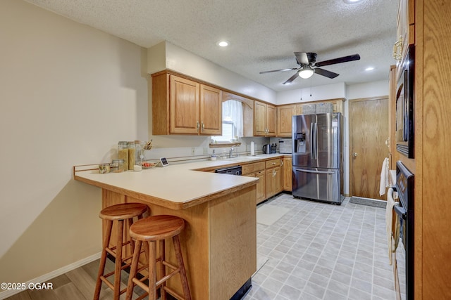 1241 Douglas Ct, Carthage, MO 64836 - kitchen featuring stainless steel fridge, a peninsula, a ceiling fan, a textured ceiling, and light countertops