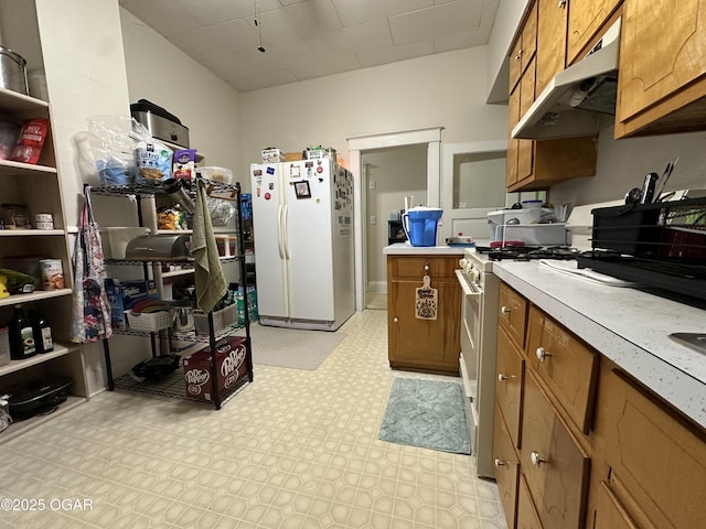 2022 S Jackson Ave, Joplin, MO 64804 - kitchen with white appliances, under cabinet range hood, brown cabinetry, light countertops, and light flooring