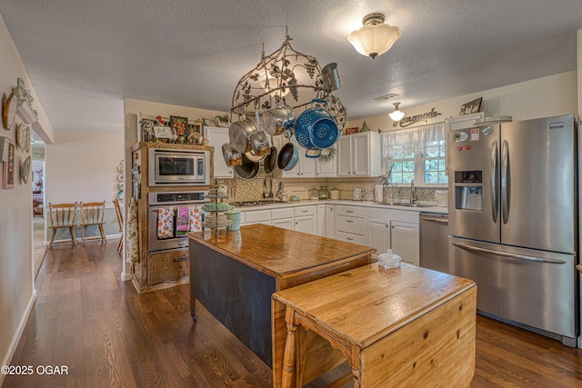 4430 E 26th St, Joplin, MO 64804 - kitchen featuring stainless steel appliances, a sink, white cabinetry, dark wood finished floors, and a textured ceiling