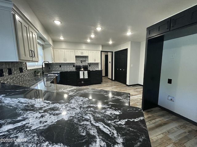 1910 Carolina Ave, Joplin, MO 64801 - kitchen with black range with electric cooktop, dark stone counters, tasteful backsplash, wood finished floors, and baseboards