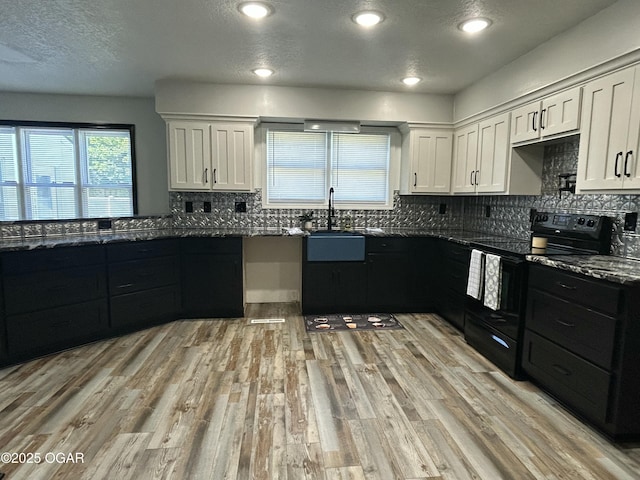 1910 Carolina Ave, Joplin, MO 64801 - kitchen with black electric range, white cabinetry, tasteful backsplash, light wood-style floors, and a textured ceiling