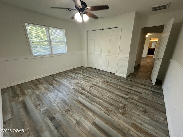 1910 Carolina Ave, Joplin, MO 64801 - unfurnished bedroom featuring wood finished floors, wainscoting, a closet, and a ceiling fan