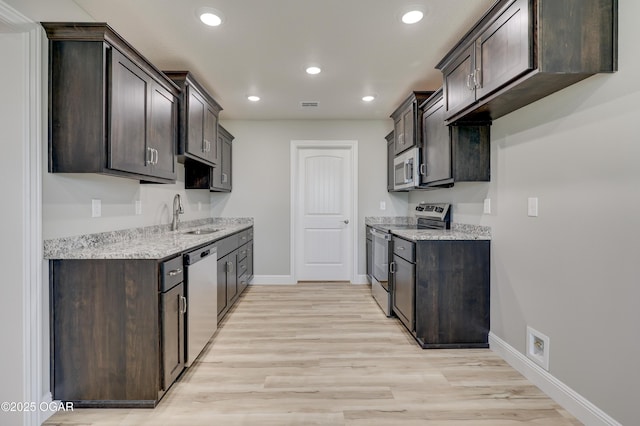 1919 Wisconsin Ave, Joplin, MO 64804 - kitchen featuring appliances with stainless steel finishes, dark brown cabinets, light wood-style floors, light stone counters, and recessed lighting